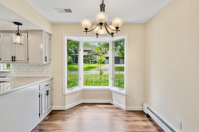 101 Sunset Dr S, Minnetonka, MN 55305 - unfurnished dining area featuring plenty of natural light, a baseboard radiator, a chandelier, wood finished floors, and a textured ceiling