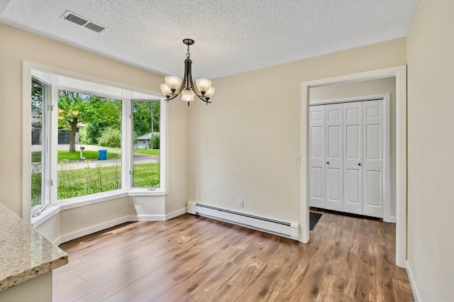 101 Sunset Dr S, Minnetonka, MN 55305 - unfurnished dining area featuring a baseboard radiator, a chandelier, wood finished floors, and a textured ceiling