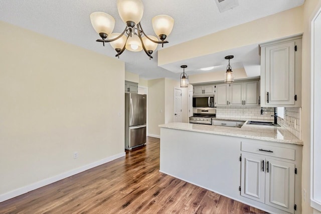 101 Sunset Dr S, Minnetonka, MN 55305 - kitchen featuring stainless steel appliances, a peninsula, dark wood finished floors, backsplash, and a chandelier