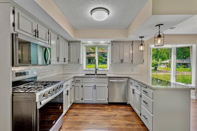 101 Sunset Dr S, Minnetonka, MN 55305 - kitchen featuring stainless steel appliances, a peninsula, a textured ceiling, wood finished floors, and light stone countertops