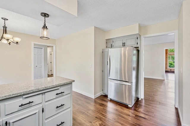 101 Sunset Dr S, Minnetonka, MN 55305 - kitchen featuring freestanding refrigerator, dark wood-type flooring, hanging light fixtures, light stone counters, and a textured ceiling