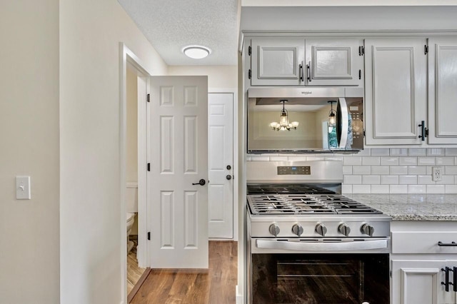 101 Sunset Dr S, Minnetonka, MN 55305 - kitchen with appliances with stainless steel finishes, wood finished floors, tasteful backsplash, light stone counters, and a chandelier