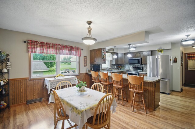 20128 554th St, Concord Twp, MN 55985 - dining area featuring light wood finished floors, a textured ceiling, wainscoting, and wooden walls