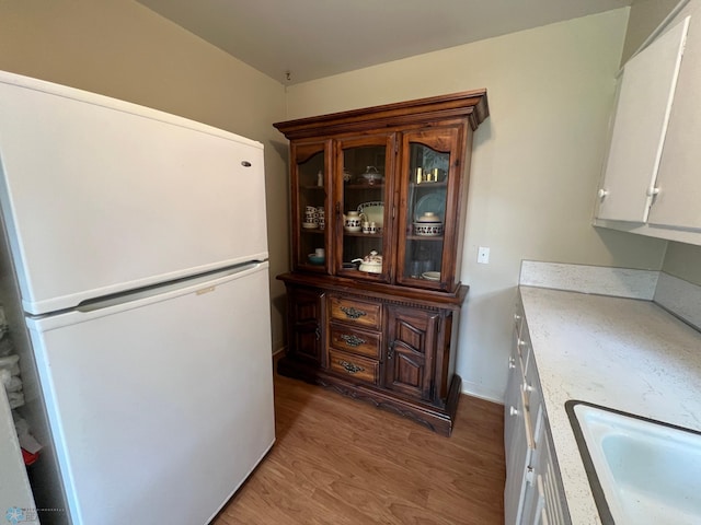 1410 4th St S, Moorhead, MN 56560 - kitchen featuring freestanding refrigerator, light wood-style floors, light countertops, glass insert cabinets, and white cabinetry