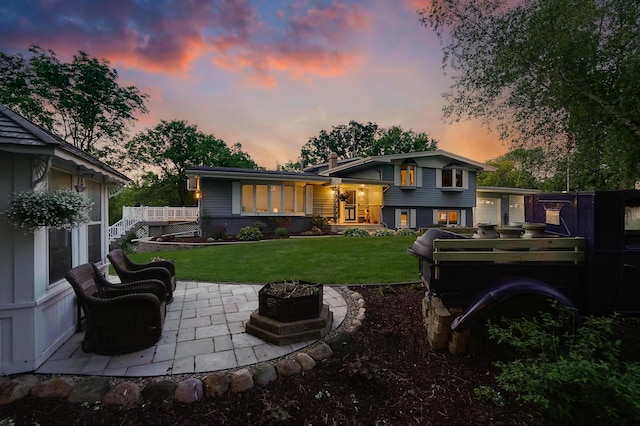 108 1st St, Kenyon, MN 55946 - back of house at dusk featuring a lawn and a patio area