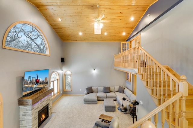 108 1st St, Kenyon, MN 55946 - carpeted living area featuring wood ceiling, stairway, high vaulted ceiling, a stone fireplace, and a ceiling fan