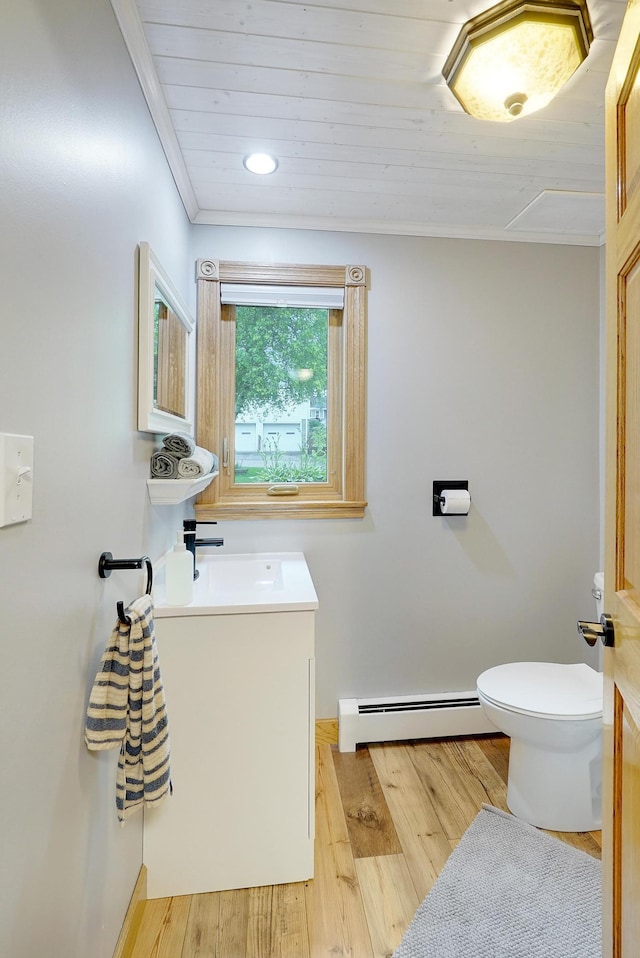 108 1st St, Kenyon, MN 55946 - half bath with a baseboard heating unit, toilet, wood finished floors, vanity, and ornamental molding