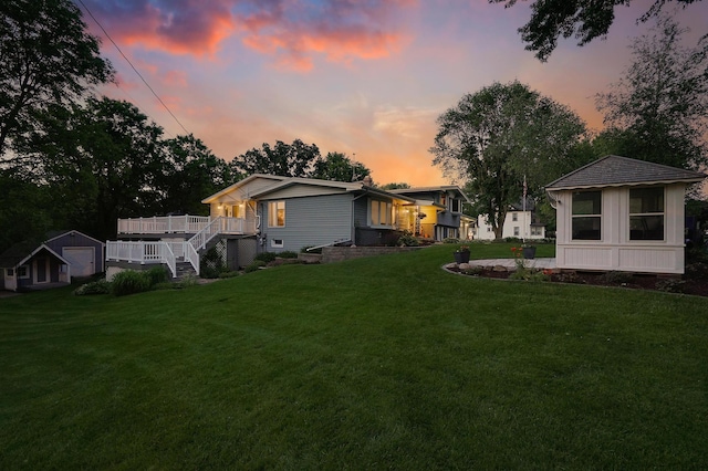108 1st St, Kenyon, MN 55946 - yard at dusk with an outdoor structure, a lawn, a deck, and a garage