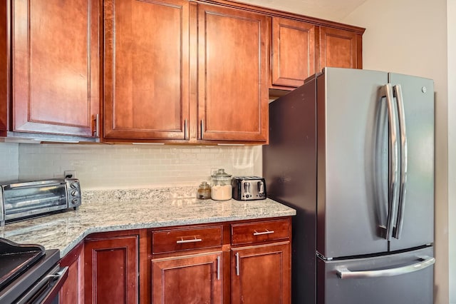12693 Collegeview Dr Unit 201, Eden Prairie, MN 55347 - kitchen featuring freestanding refrigerator, decorative backsplash, light stone counters, and brown cabinets