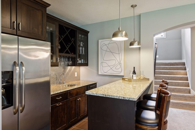 3365 Osgood Way N, Baytown Twp, MN 55082 - kitchen with stainless steel fridge, tasteful backsplash, glass insert cabinets, dark brown cabinetry, and a kitchen breakfast bar