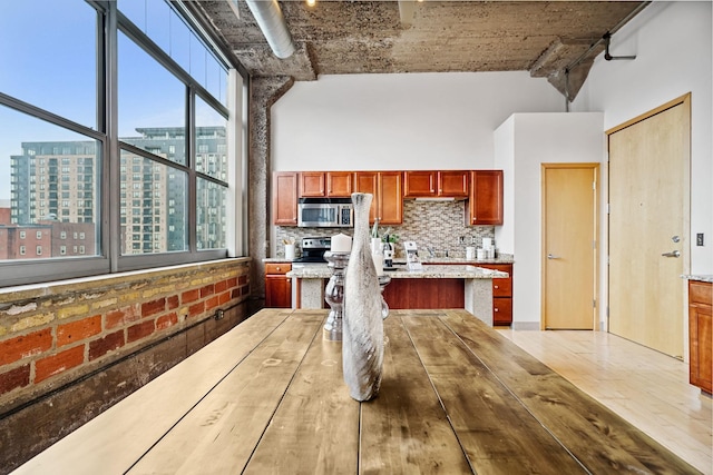 521 7th St Unit 420, Minneapolis, MN 55415 - kitchen with stainless steel microwave, healthy amount of natural light, decorative backsplash, and a towering ceiling