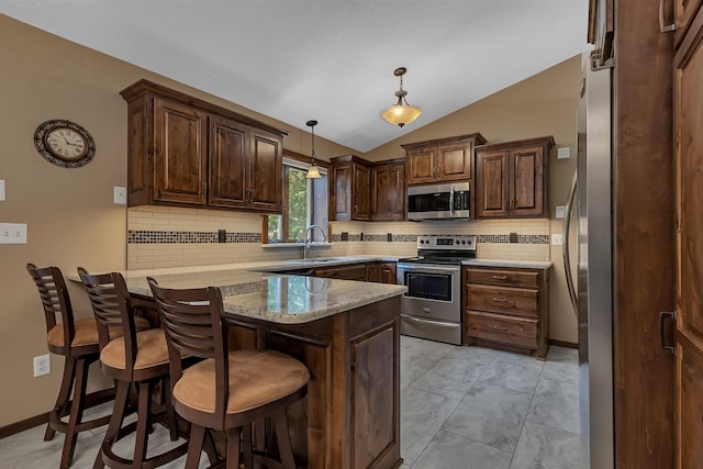 1213 4 1/2 Ave N, Sauk Rapids, MN 56379 - kitchen with stainless steel appliances, vaulted ceiling, a peninsula, decorative backsplash, and a breakfast bar