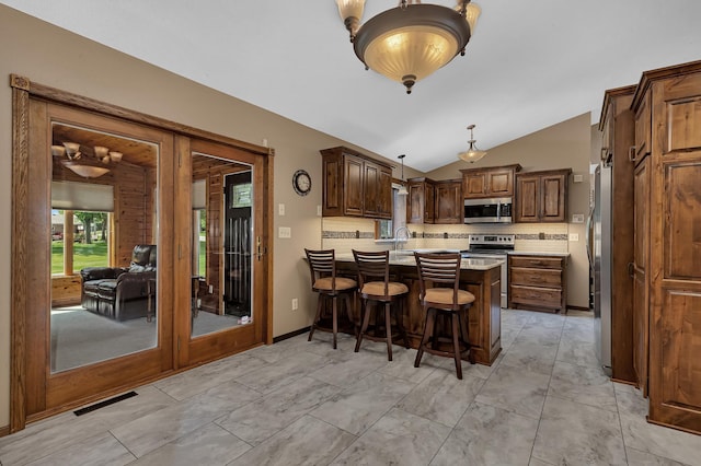 1213 4 1/2 Ave N, Sauk Rapids, MN 56379 - kitchen featuring stainless steel appliances, a peninsula, vaulted ceiling, a kitchen breakfast bar, and light countertops