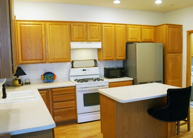 2009 Stahlke Way Unit 15, Chaska, MN 55318 - kitchen with white range with gas cooktop, freestanding refrigerator, black microwave, under cabinet range hood, and light countertops