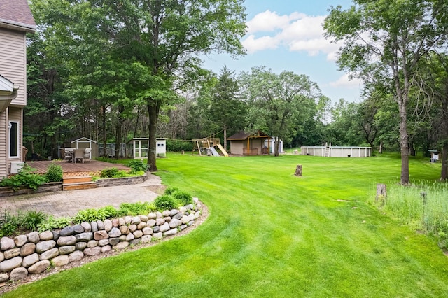 18250 221st Ave NW, Big Lake, MN 55309 - view of green lawn featuring a storage shed, a deck, a playground, and view of scattered trees