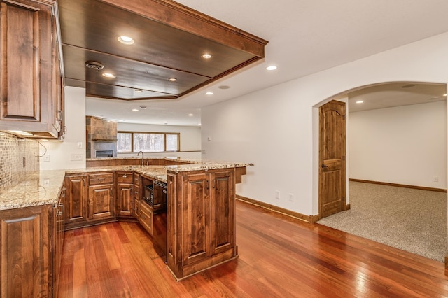 18250 221st Ave NW, Big Lake, MN 55309 - kitchen with a peninsula, dark wood-style flooring, arched walkways, light stone counters, and recessed lighting