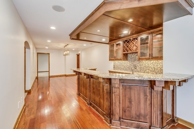 18250 221st Ave NW, Big Lake, MN 55309 - indoor wet bar with backsplash, light wood-style flooring, arched walkways, recessed lighting, and pendant lighting