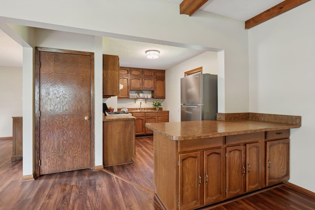 7507 Blaisdell Ave, Richfield, MN 55423 - kitchen with freestanding refrigerator, brown cabinets, a peninsula, dark wood-style floors, and beam ceiling