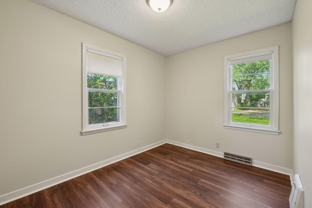 7507 Blaisdell Ave, Richfield, MN 55423 - unfurnished room featuring dark wood-style flooring, healthy amount of natural light, a baseboard radiator, and a textured ceiling