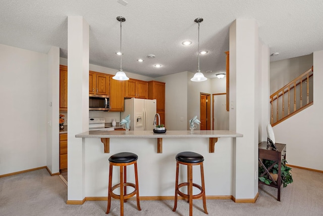 10794 Hawthorn Trl Unit A, Woodbury, MN 55129 - kitchen featuring white appliances, light colored carpet, a breakfast bar area, brown cabinetry, and a peninsula
