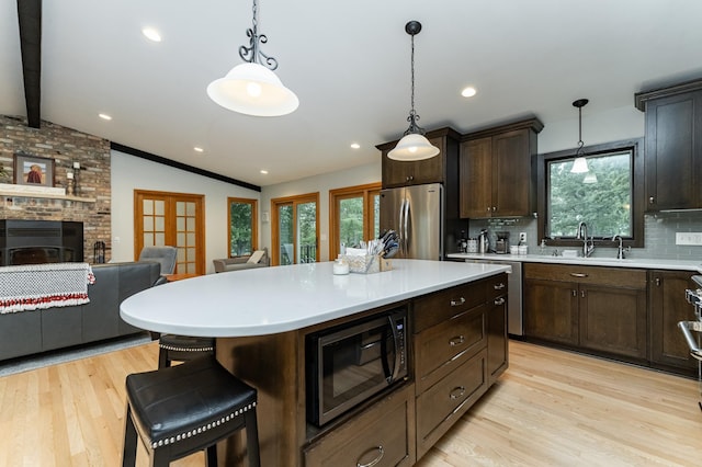 25 Conway Ct SE, Rochester Twp, MN 55904 - kitchen featuring appliances with stainless steel finishes, light wood-type flooring, light countertops, backsplash, and open floor plan