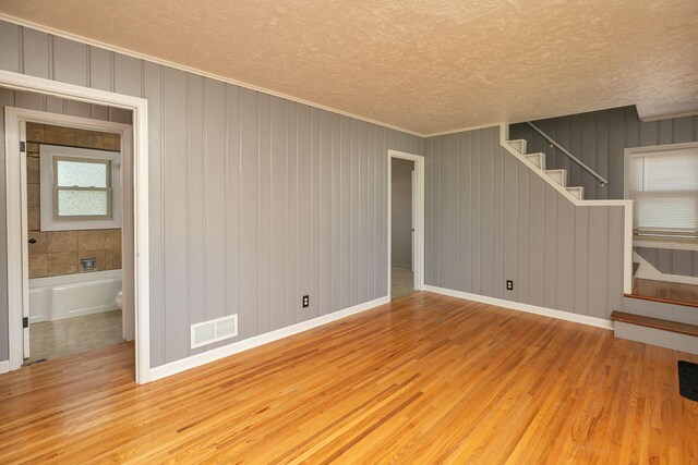 2010 Oakland Ave, Austin, MN 55912 - unfurnished living room featuring wood finished floors, stairs, a textured ceiling, and ornamental molding