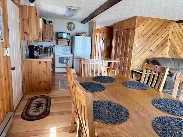 12981 Arcadia Ct NE, Turtle Lake Twp, MN 56601 - dining space featuring baseboard heating, a textured ceiling, light wood-type flooring, beamed ceiling, and wood walls