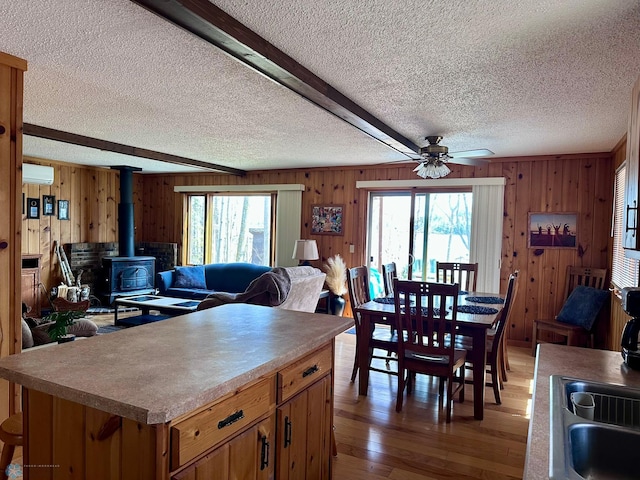 12981 Arcadia Ct NE, Turtle Lake Twp, MN 56601 - dining room featuring an AC wall unit, a wood stove, a textured ceiling, wooden walls, and ceiling fan