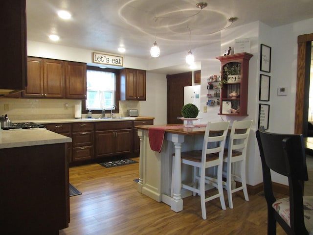 401 St Paul Ave, Fulda, MN 56131 - kitchen with wood finished floors, a peninsula, light countertops, and a breakfast bar area