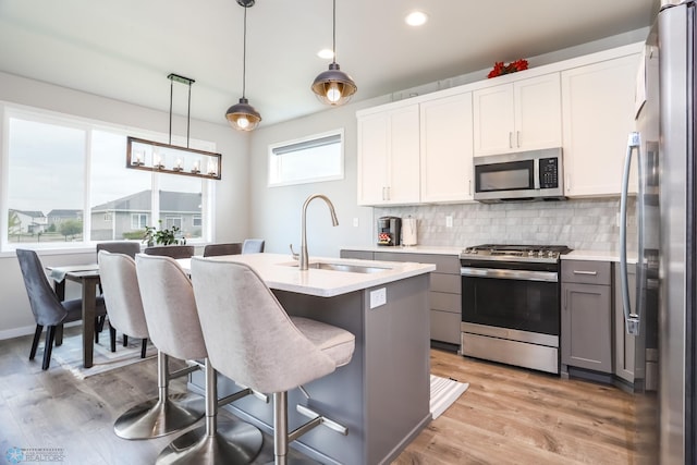 1326 Commander Dr W, West Fargo, ND 58078 - kitchen with stainless steel appliances, decorative backsplash, light countertops, light wood-type flooring, and gray cabinetry