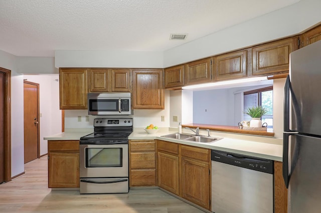3801 98th St Unit 108, Bloomington, MN 55431 - kitchen with stainless steel appliances, light countertops, brown cabinetry, and a textured ceiling
