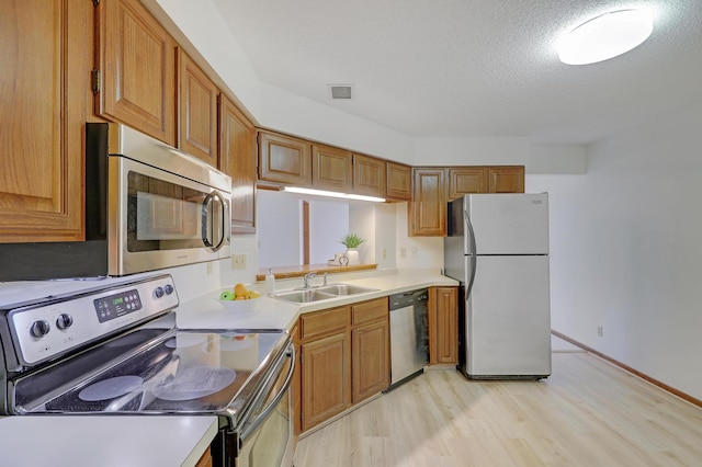 3801 98th St Unit 108, Bloomington, MN 55431 - kitchen with stainless steel appliances, light wood-style floors, light countertops, brown cabinetry, and a textured ceiling