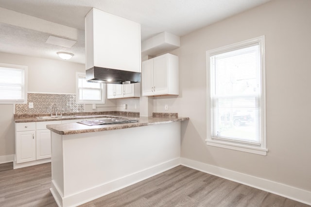 1303 Fremont Ave, Saint Paul, MN 55106 - kitchen with light wood-style floors, white cabinets, a peninsula, and cooktop