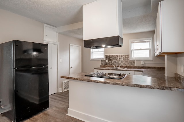 1303 Fremont Ave, Saint Paul, MN 55106 - kitchen featuring freestanding refrigerator, dark countertops, a peninsula, electric stovetop, and white cabinetry
