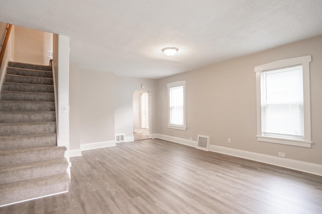 1303 Fremont Ave, Saint Paul, MN 55106 - empty room featuring wood finished floors, stairs, arched walkways, and a textured ceiling