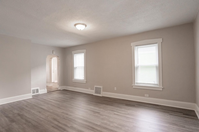 1303 Fremont Ave, Saint Paul, MN 55106 - unfurnished room with a textured ceiling, dark wood finished floors, and arched walkways