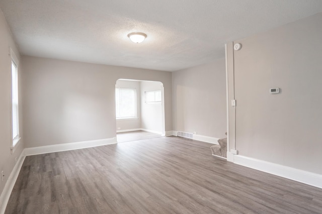 1303 Fremont Ave, Saint Paul, MN 55106 - spare room with wood finished floors, arched walkways, and a textured ceiling