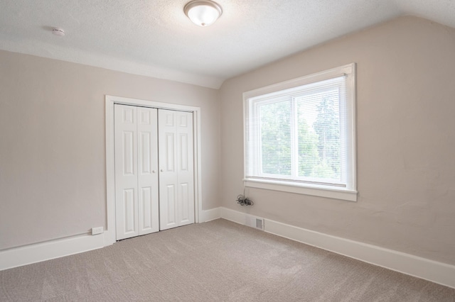1303 Fremont Ave, Saint Paul, MN 55106 - unfurnished bedroom featuring light carpet, a closet, vaulted ceiling, and a textured ceiling
