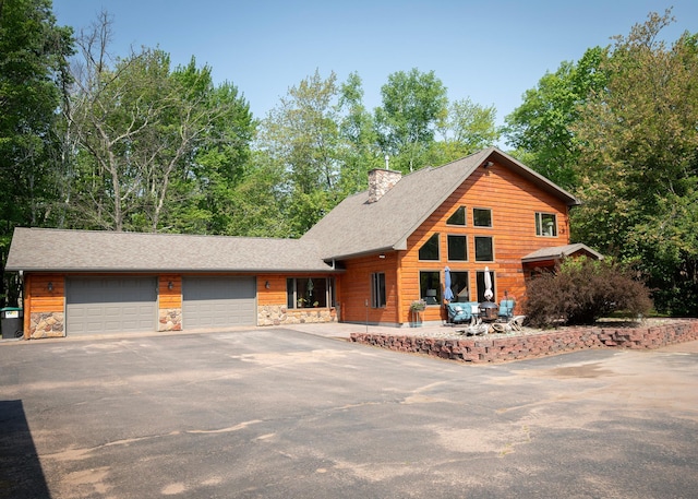 9777 Gruhlke Rd, Summit Twp, WI 54836 - view of front of property with driveway, an attached garage, stone siding, and a chimney