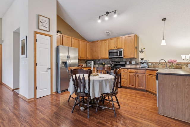 8547 Grove Cir, Shakopee, MN 55379 - kitchen featuring appliances with stainless steel finishes, vaulted ceiling, wood finished floors, backsplash, and a peninsula