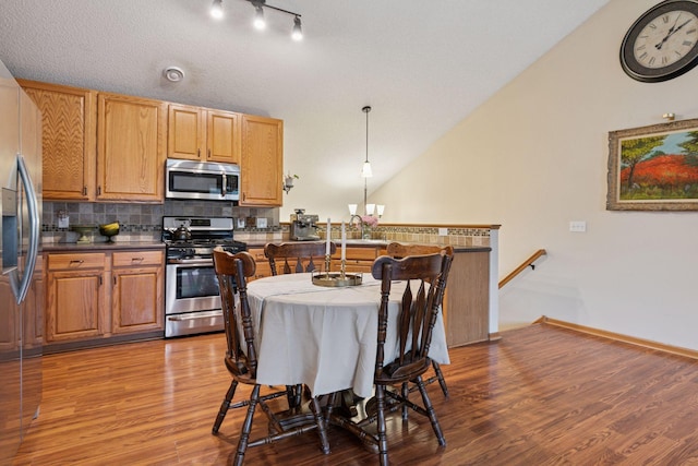 8547 Grove Cir, Shakopee, MN 55379 - kitchen featuring appliances with stainless steel finishes, dark countertops, wood finished floors, decorative backsplash, and lofted ceiling