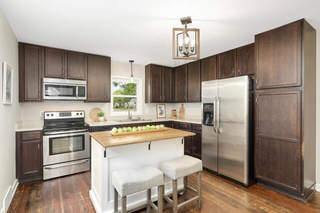 333 3rd St NE, Osseo, MN 55369 - kitchen with appliances with stainless steel finishes, dark wood-style floors, dark brown cabinets, a kitchen island, and pendant lighting