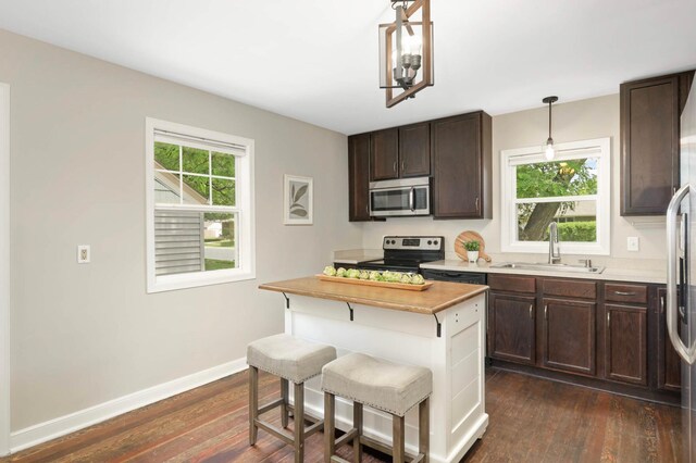 333 3rd St NE, Osseo, MN 55369 - kitchen with appliances with stainless steel finishes, dark brown cabinetry, dark wood-style flooring, and a kitchen bar