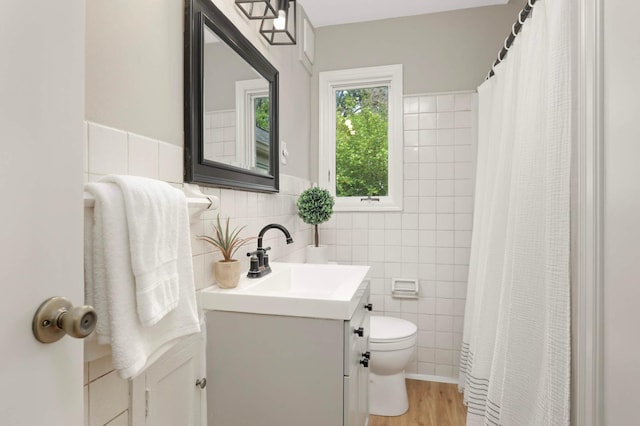 333 3rd St NE, Osseo, MN 55369 - full bathroom featuring tile walls, vanity, wood finished floors, a shower with shower curtain, and a wainscoted wall