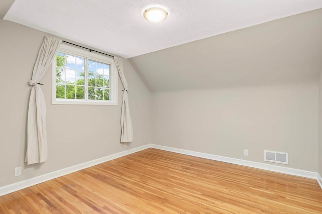333 3rd St NE, Osseo, MN 55369 - additional living space featuring light wood-style flooring, vaulted ceiling, and a textured ceiling