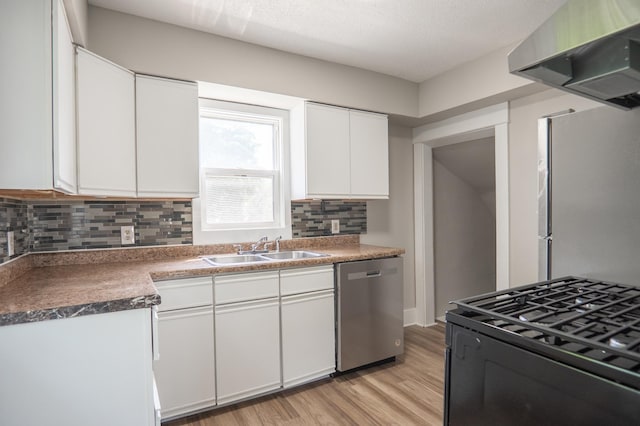 938 Cypress St, Saint Paul, MN 55106 - kitchen with appliances with stainless steel finishes, wall chimney exhaust hood, light wood-style flooring, backsplash, and white cabinetry