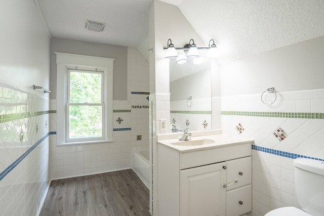 938 Cypress St, Saint Paul, MN 55106 - bathroom featuring tile walls, vanity, a textured ceiling, wood finished floors, and a wainscoted wall