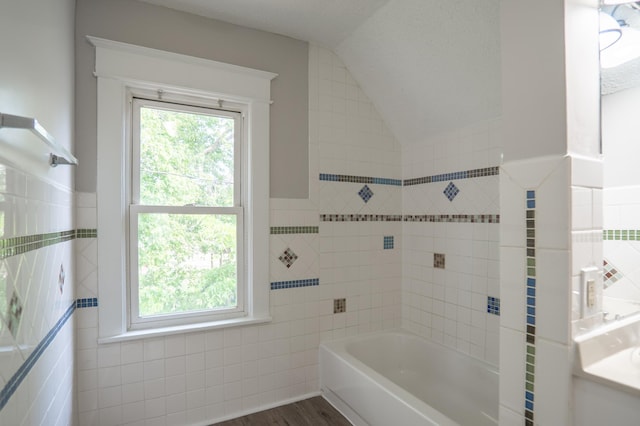 938 Cypress St, Saint Paul, MN 55106 - full bath featuring tile walls, vaulted ceiling, plenty of natural light, and wood finished floors