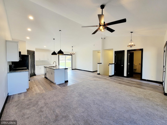 217 Bouldercrest Ave NE, Owatonna, MN 55060 - kitchen featuring light wood finished floors, vaulted ceiling, open floor plan, tasteful backsplash, and a ceiling fan