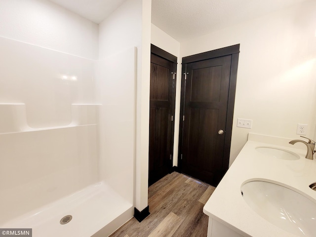217 Bouldercrest Ave NE, Owatonna, MN 55060 - full bathroom featuring wood finished floors, double vanity, and a shower